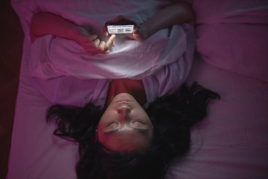 A woman lying in bed browsing her phone and doomscrolling.